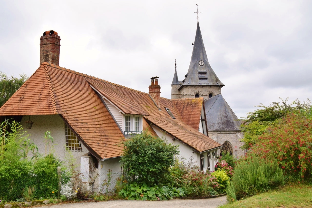 フランス北部ノルマンディー地方の風景。伝統的な赤い屋根の家と教会。
